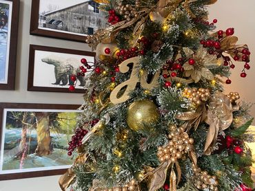 Close-up of a Christmas tree with gold and red decorations and warm lights indoors.
