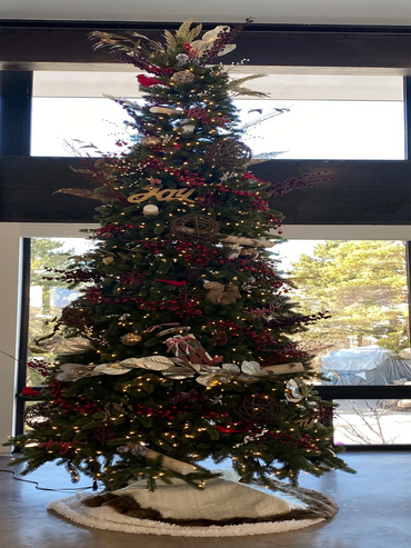 Tall Christmas tree decorated with lights, berries, and rustic ornaments indoors.
