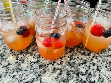 Mason jars with iced fruit drinks on a granite countertop.