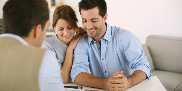 A couple smiling while discussing documents with a professional.