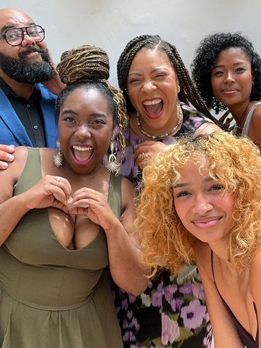 A joyful group of five friends posing and smiling for a photo indoors.