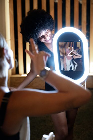Two women taking a fun photo with a lighted mirror at night.