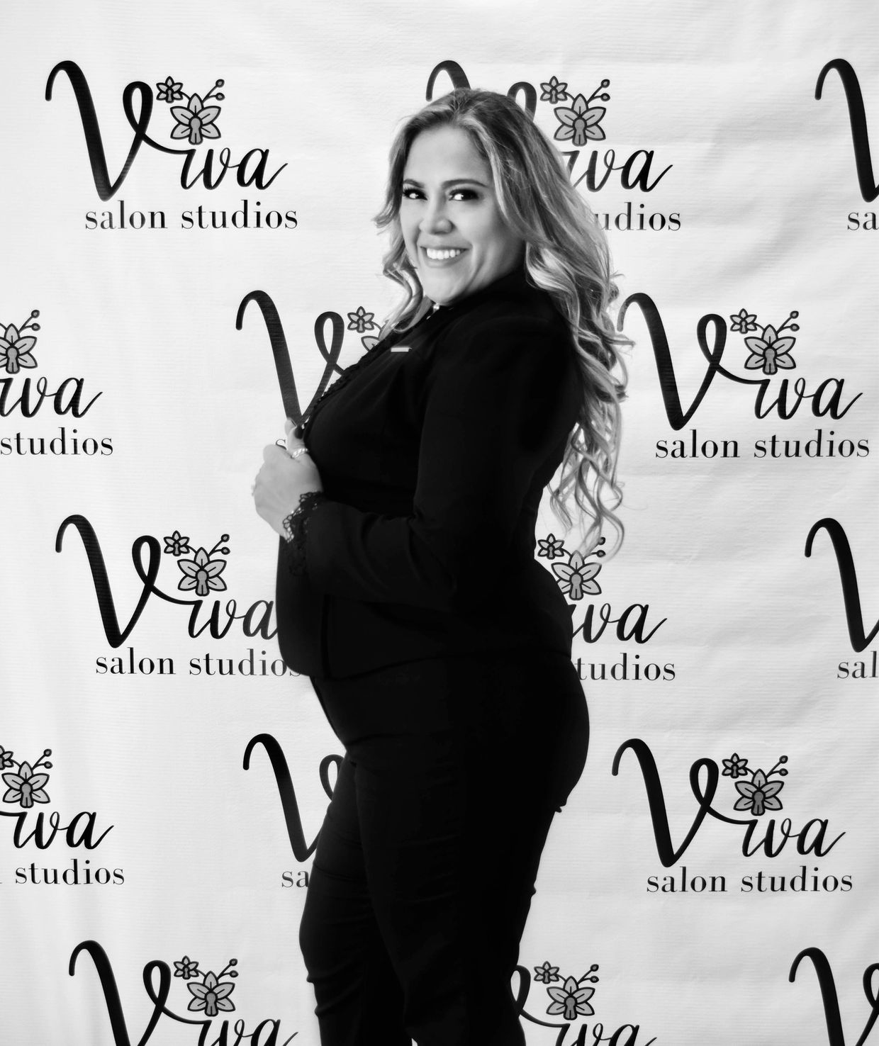 Smiling woman posing confidently at Viva Salon Studios backdrop.
