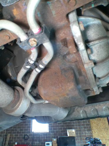 Close-up of rusty vehicle undercarriage with pipes and exhaust system.