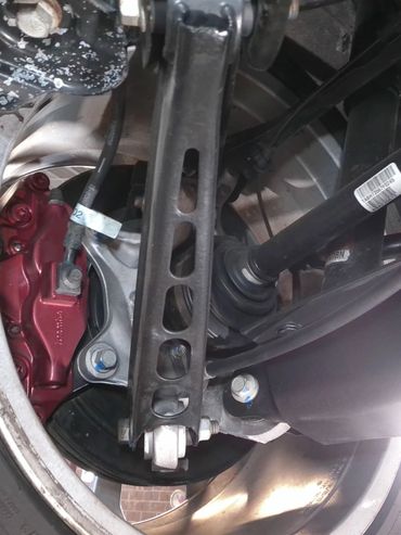 Close-up of a car's rear suspension and brake assembly with a red caliper.