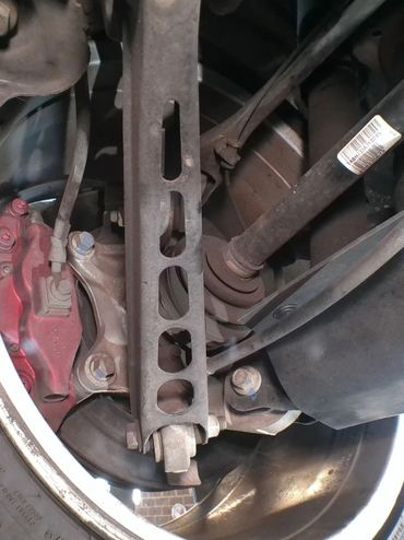 Close-up of a car's rear suspension and brake system with a worn tire and red brake caliper.