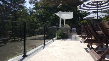 Outdoor patio with lounge chairs, umbrellas, and a view of trees.