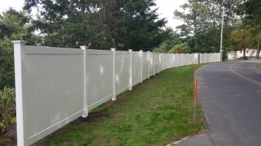 Long white fence along a curved road.