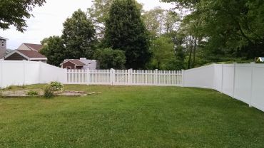 Backyard with white picket fence and green grass.