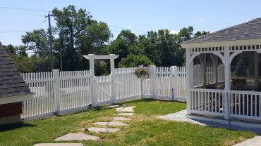 Backyard with white fence and screened gazebo.