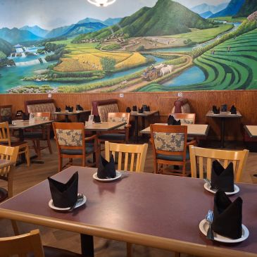 Restaurant interior with a mural of a countryside landscape.