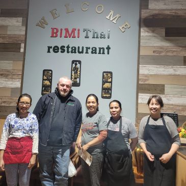 Group photo at BiMi Thai restaurant with welcoming sign.