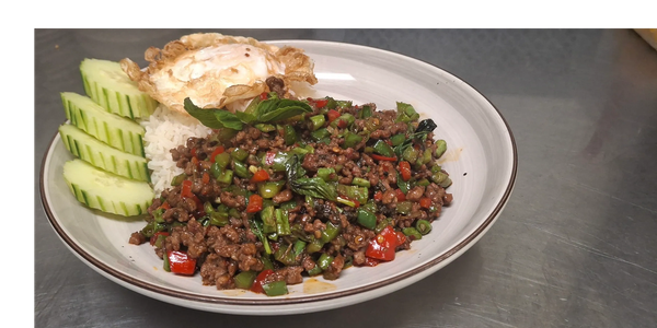 Thai dish with minced meat, green vegetables, rice, fried egg, and cucumber slices.