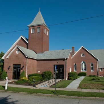 Red brick church building with a tower under a clear blue sky.