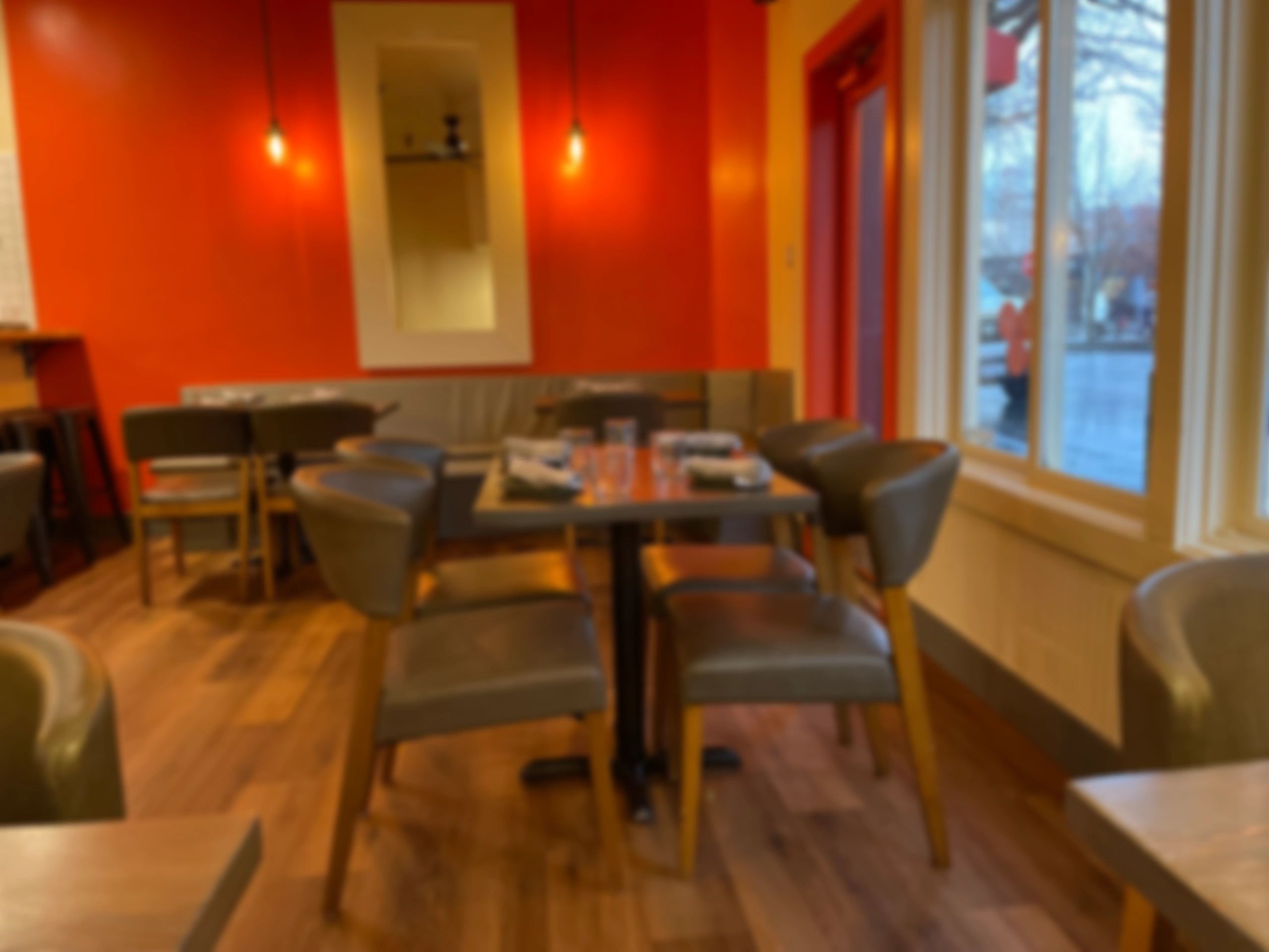 Empty outdoor cafe tables with potted plants on a brick patio.