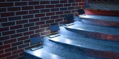 A night photo of four Step Edge Lanterns located on a patio stairway.