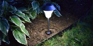 A photo of a Shade Solar Light illuminating a garden at night.
