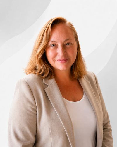 Professional woman in beige blazer smiling against a light background.