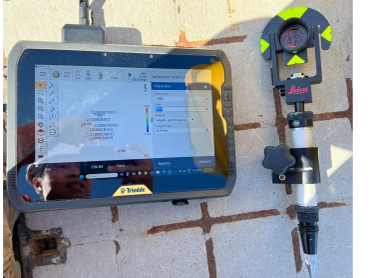 Trimble field controller and Leica prism pole set up over a marked survey control point on a Sydney