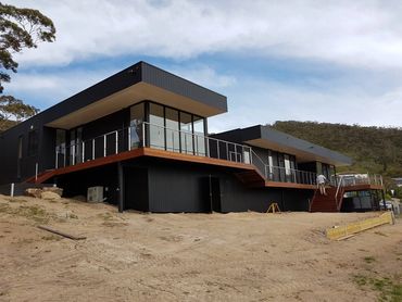 Exterior painting of modern black home with timber stairs in McCrae