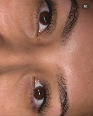 Close-up of a person's brown eyes and natural eyebrows with visible skin texture.
