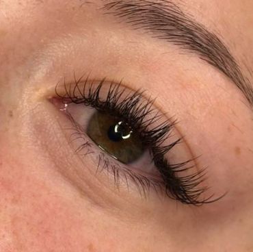 Close-up of a brown eye with long eyelashes and a well-groomed eyebrow.