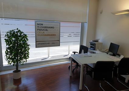 Tavolo con sedie su parquet, vetrina e pianta