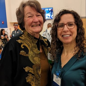 Two smiling women posing indoors at an event.