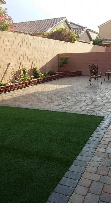 square shaped trimmed grass next to a brick tile floor, and a couple of chairs