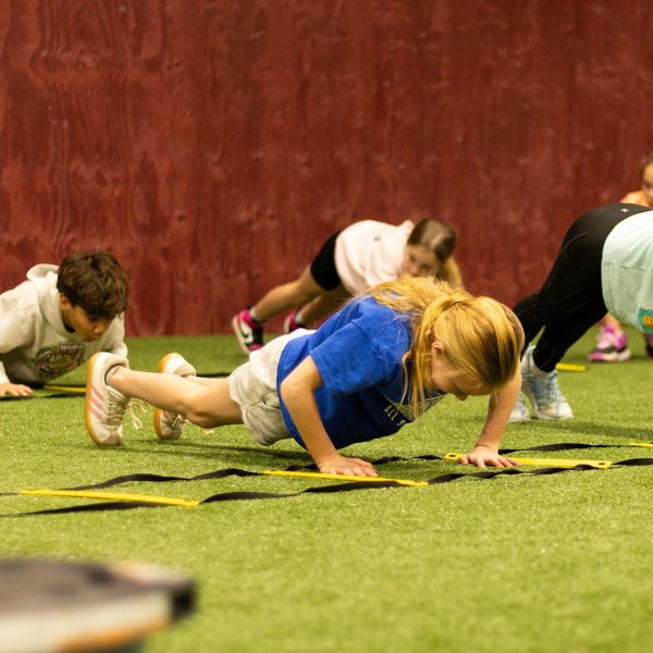 Kids exercising on agility ladders indoors.