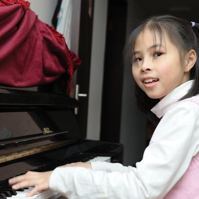 A little girl playing piano and smiling
