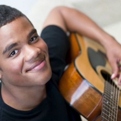A youth playing left handed guitar.
