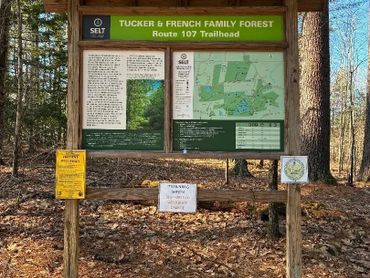 Trailhead sign for Tucker & French Family Forest with maps and safety notices.