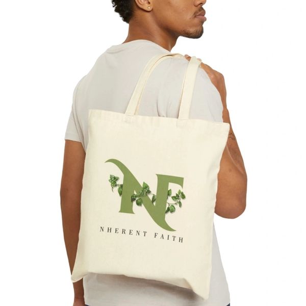 Man carrying beige tote bag with green floral 'NF' logo and 'NHERENT FAITH' text.