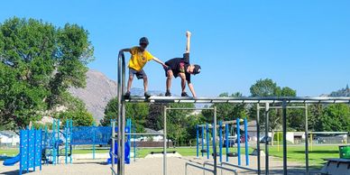 Two boys playing on playground bars.