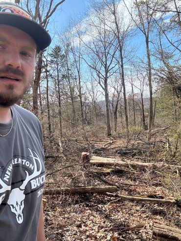 Man in a forest clearing with blue sky.