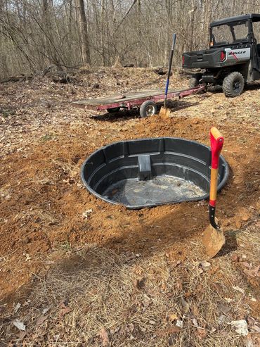 Outdoor scene with a utility vehicle, trailer, and dug hole.