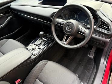 Interior of a Mazda car with leather steering and modern controls.