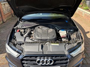 Open hood showing Audi car engine and front grille.