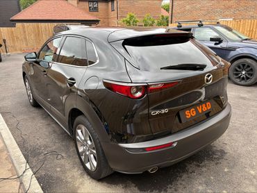 Rear view of a black Mazda CX-30 parked in a driveway.