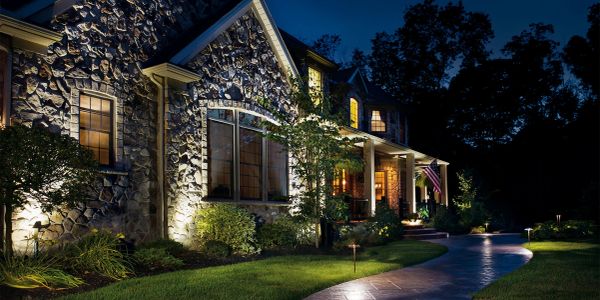 A stone house illuminated at night with a curved walkway.