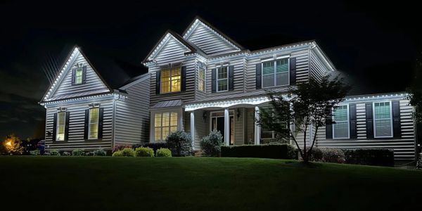 A well-lit suburban house at night with white lights.