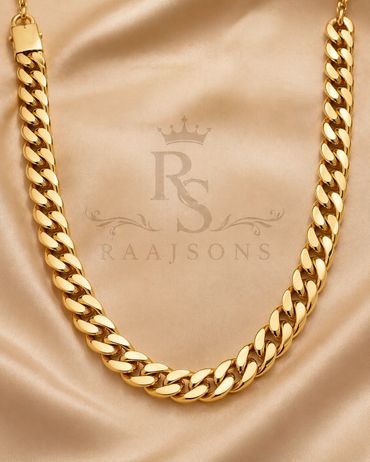 Elegant gold Cuban link chain on beige satin fabric.