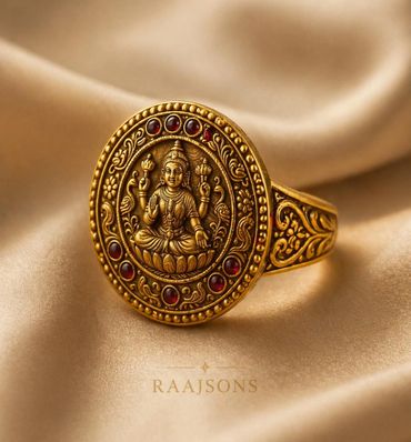 Intricately designed gold ring with deity engraving and red gemstones.