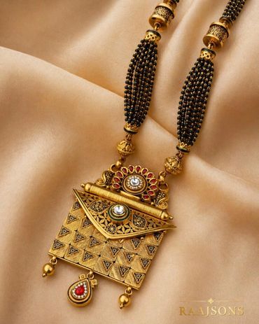 Elegant gold and black beaded necklace with intricate pendant design.