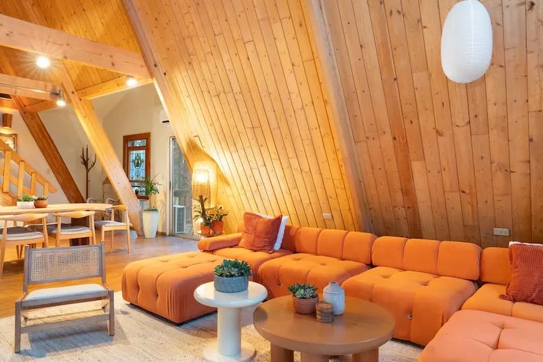 Cozy wooden attic living room with orange sofa.