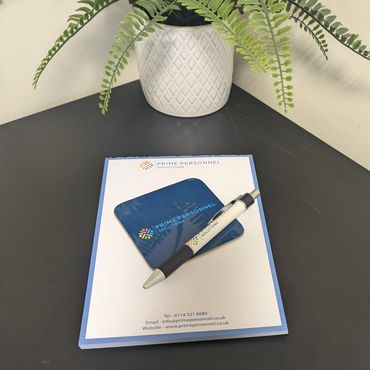 Desk setup with Prime Personnel Solutions stationery and a potted plant.