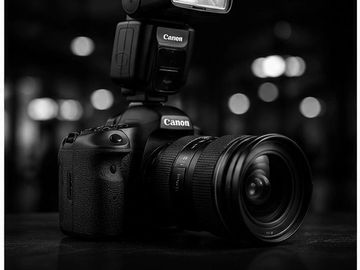 Black Canon DSLR camera with flash on a dark surface.