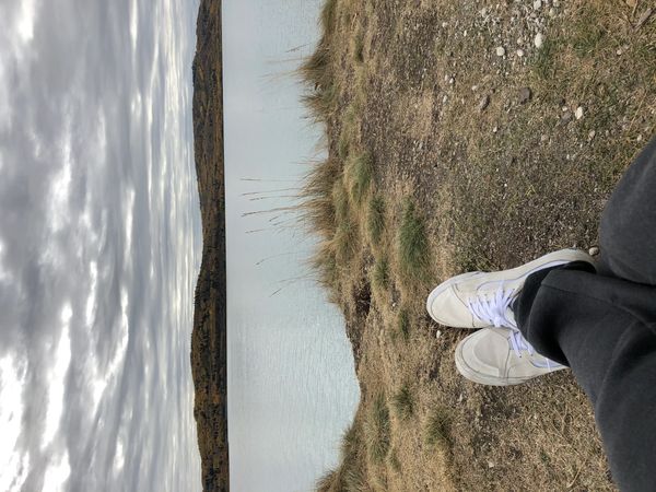 Person relaxing by a calm lake with cloudy skies.