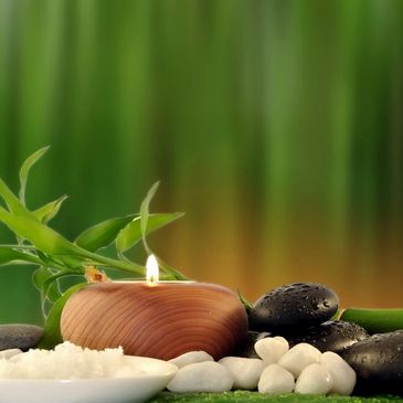 Spa setting with candle, stones, and bamboo leaves.